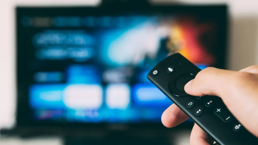 Пульт у руці перед телевізором